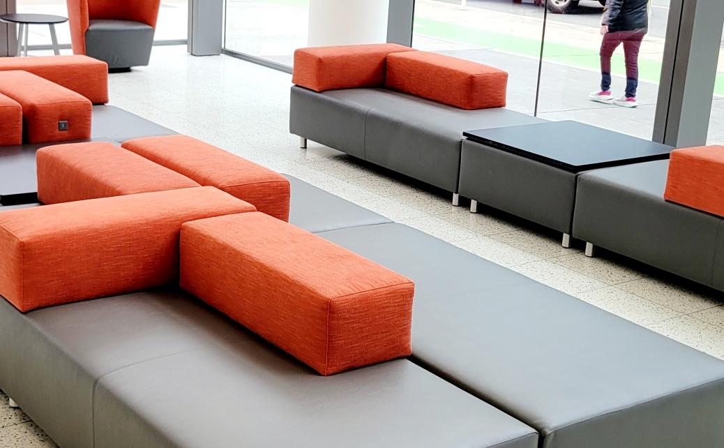grey & orange lounge furniture in a bright area of the lobby with windows viewing the sidewalk